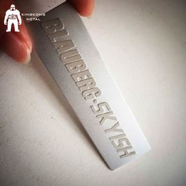 El laser grabó las pequeñas etiquetas del metal del acero inoxidable para el azul de los bolsos/el color de Brown